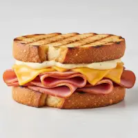 Ham & Gruyere Melt from the First Watch Breakfast Menu with Prices, featuring smoked ham, melted Gruyere cheese, tomato, and Dijon mayo on grilled artisan bread.