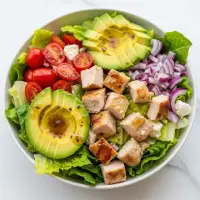 Chicken Avocado Chop Salad from the First Watch Breakfast Menu with Prices, featuring grilled chicken, avocado, black beans, corn, tomatoes, and feta cheese on fresh greens with citrus chipotle dressing.