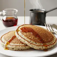 Two Multigrain Pancakes from the First Watch Breakfast Menu with Prices, served golden brown with a side of butter and syrup